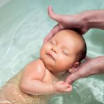 Первое купание новорожденного в ванночке.