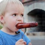 A child tries a sausage