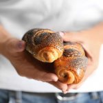 fresh buns with poppy seeds in hands
